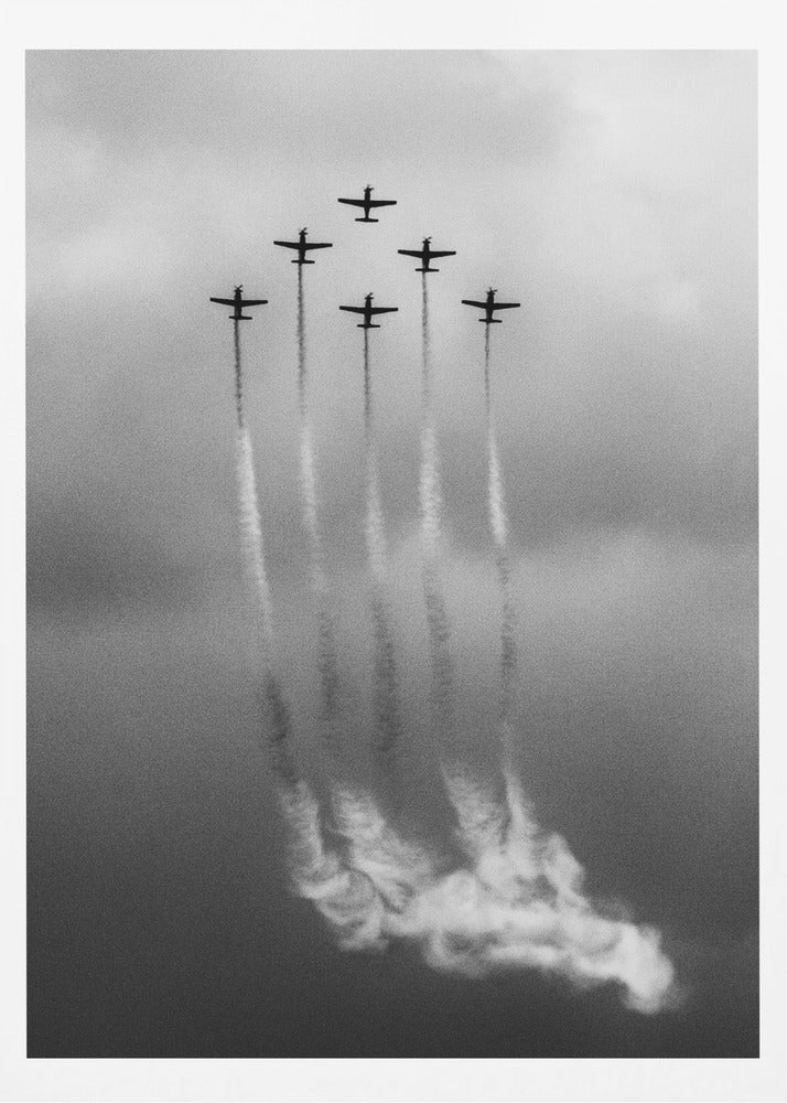 A grainy black and white photo of six airplanes flying in a V-formation against a cloudy sky. Each plane leaves a long, white smoke trail that billows at the bottom of the frame. The image is presented within a black border. Print