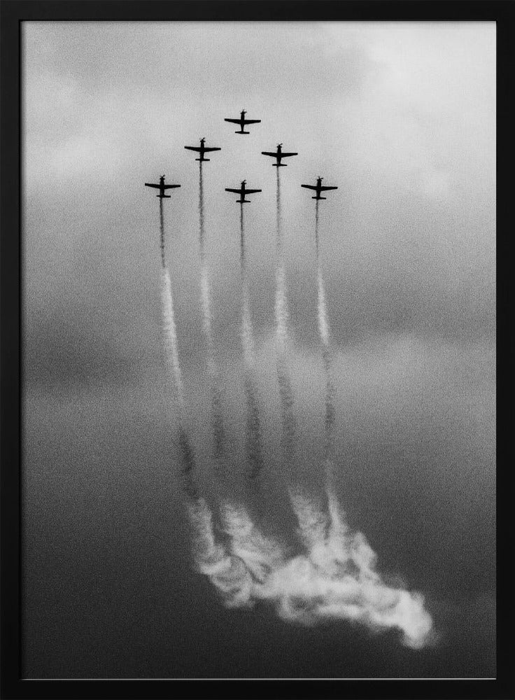 A grainy black and white photo of six airplanes flying in a V-formation against a cloudy sky. Each plane leaves a long, white smoke trail that billows at the bottom of the frame. The image is presented within a black border. Print