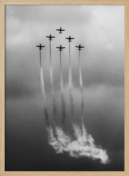 A grainy black and white photo of six airplanes flying in a V-formation against a cloudy sky. Each plane leaves a long, white smoke trail that billows at the bottom of the frame. The image is presented within a black border. Print