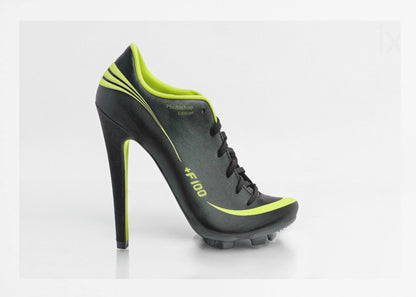 A conceptual piece of digital art featuring a hybrid shoe that is part black soccer cleat and part stiletto high heel. The shoe has neon lime green accents and is displayed against a stark white background inside a silver frame. Decor