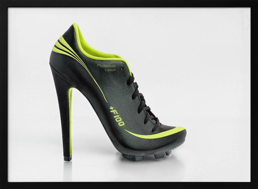 A conceptual piece of digital art featuring a hybrid shoe that is part black soccer cleat and part stiletto high heel. The shoe has neon lime green accents and is displayed against a stark white background inside a silver frame. Decor