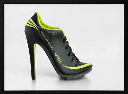A conceptual piece of digital art featuring a hybrid shoe that is part black soccer cleat and part stiletto high heel. The shoe has neon lime green accents and is displayed against a stark white background inside a silver frame. Decor