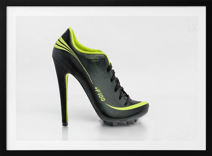 A conceptual piece of digital art featuring a hybrid shoe that is part black soccer cleat and part stiletto high heel. The shoe has neon lime green accents and is displayed against a stark white background inside a silver frame. Decor