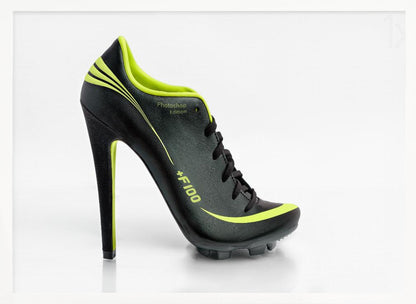 A conceptual piece of digital art featuring a hybrid shoe that is part black soccer cleat and part stiletto high heel. The shoe has neon lime green accents and is displayed against a stark white background inside a silver frame. Decor