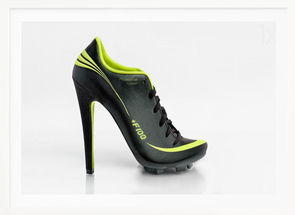 A conceptual piece of digital art featuring a hybrid shoe that is part black soccer cleat and part stiletto high heel. The shoe has neon lime green accents and is displayed against a stark white background inside a silver frame. Decor