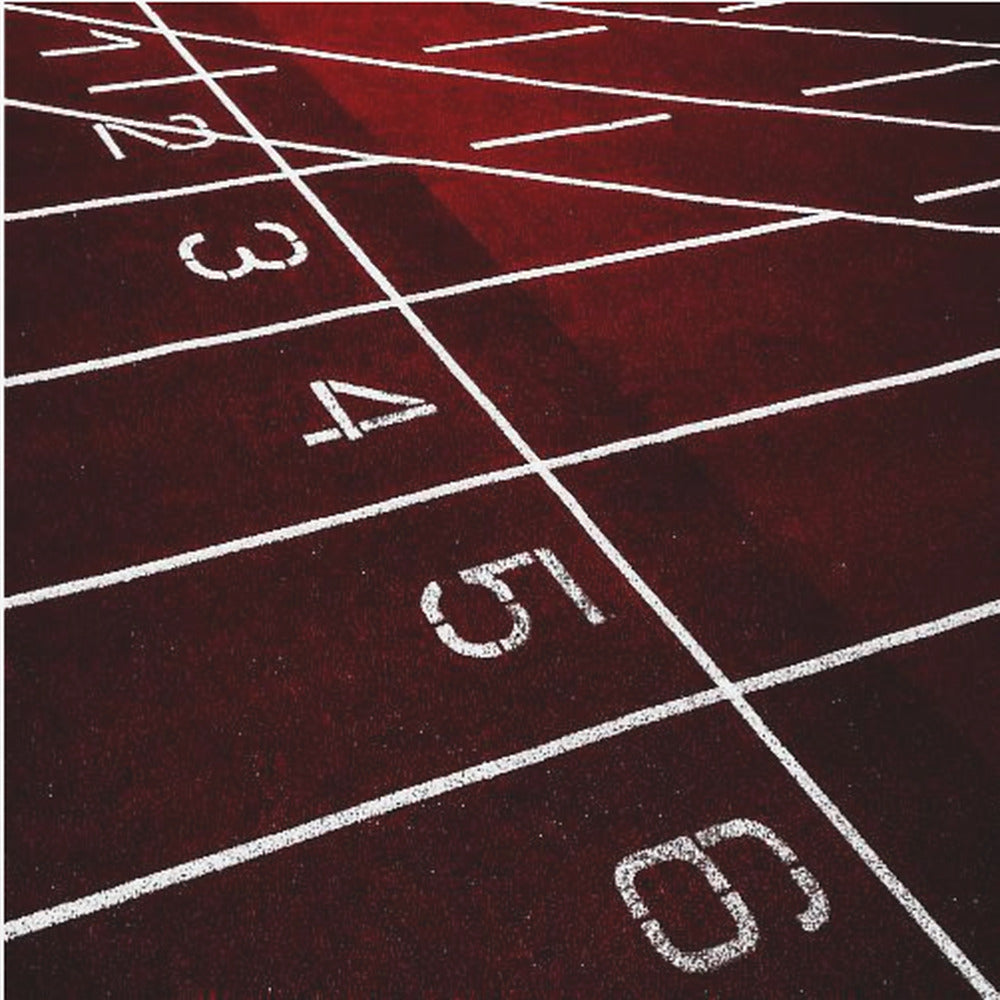A framed, high-angle photograph of a deep red running track, showing the white lines and numbers for lanes one through six creating a grid-like pattern. Poster