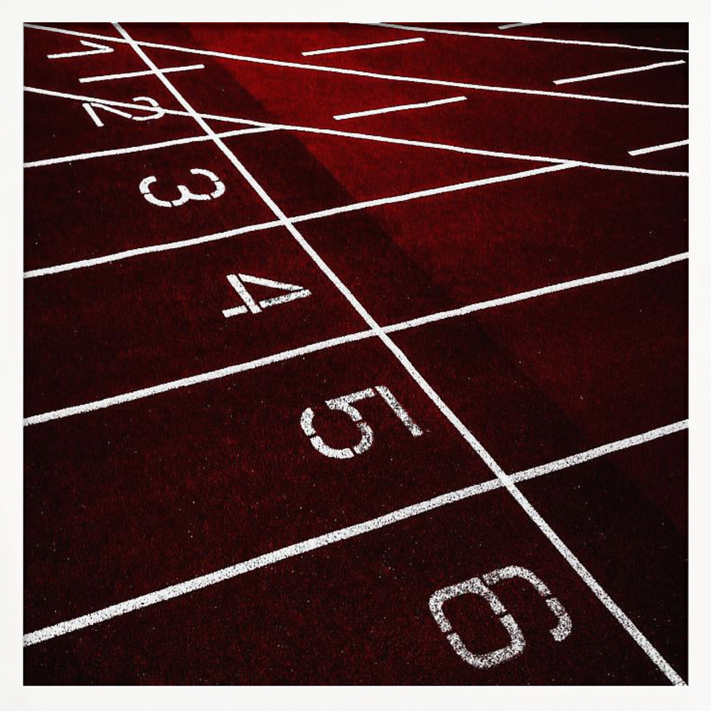 A framed, high-angle photograph of a deep red running track, showing the white lines and numbers for lanes one through six creating a grid-like pattern. Poster