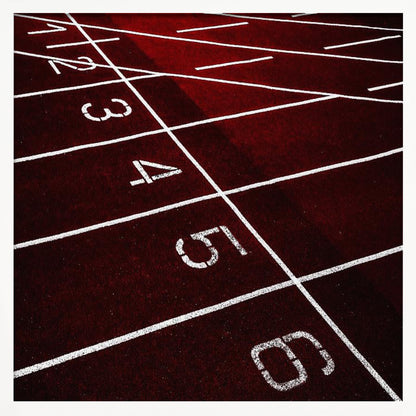 A framed, high-angle photograph of a deep red running track, showing the white lines and numbers for lanes one through six creating a grid-like pattern. Poster