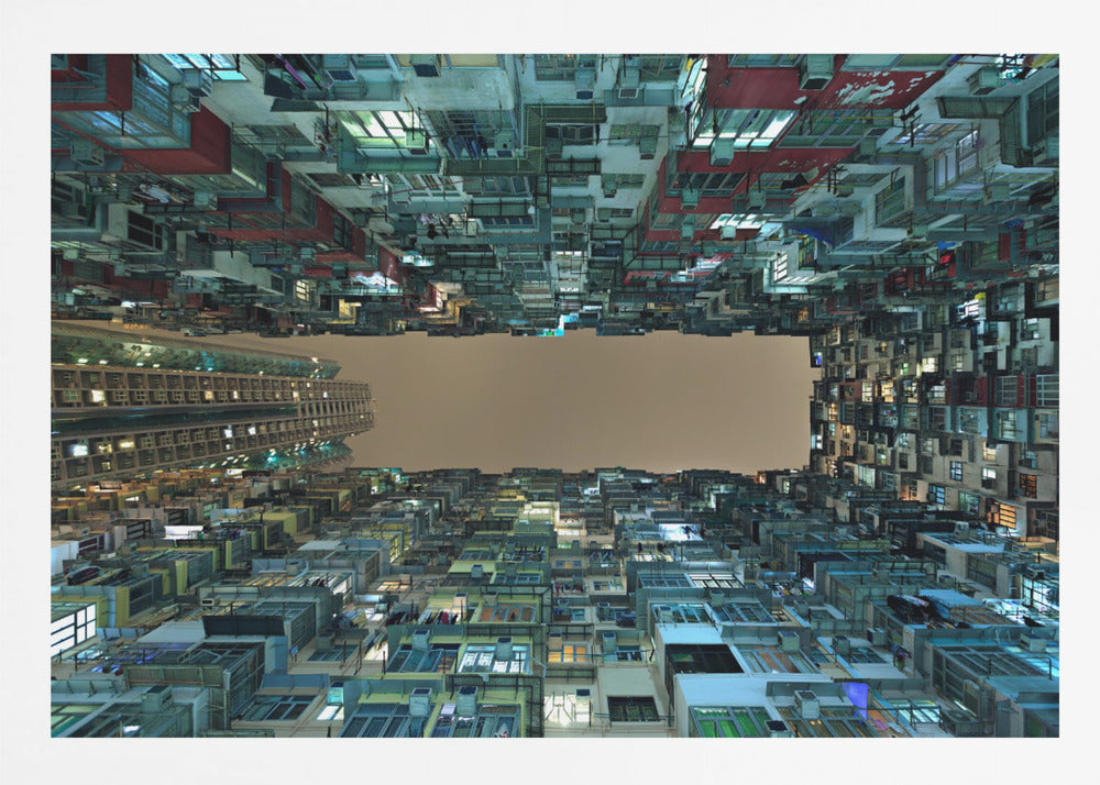 A framed, low-angle photograph looking up from a courtyard at densely packed, colorful apartment buildings that form a rectangle around a blank, overcast sky at night. Print
