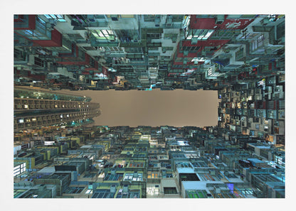A framed, low-angle photograph looking up from a courtyard at densely packed, colorful apartment buildings that form a rectangle around a blank, overcast sky at night. Print