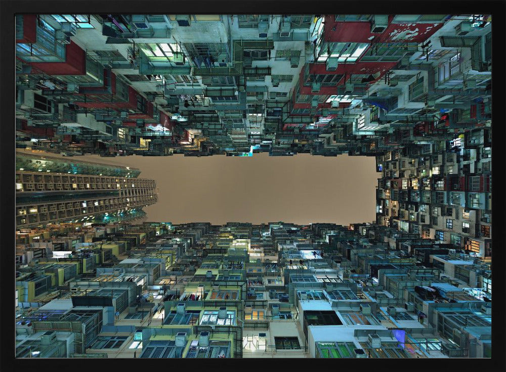 A framed, low-angle photograph looking up from a courtyard at densely packed, colorful apartment buildings that form a rectangle around a blank, overcast sky at night. Print