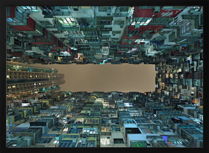 A framed, low-angle photograph looking up from a courtyard at densely packed, colorful apartment buildings that form a rectangle around a blank, overcast sky at night. Print