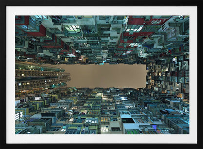A framed, low-angle photograph looking up from a courtyard at densely packed, colorful apartment buildings that form a rectangle around a blank, overcast sky at night. Print