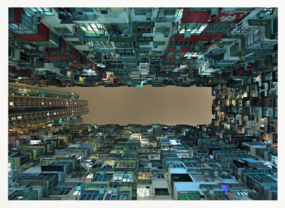 A framed, low-angle photograph looking up from a courtyard at densely packed, colorful apartment buildings that form a rectangle around a blank, overcast sky at night. Print