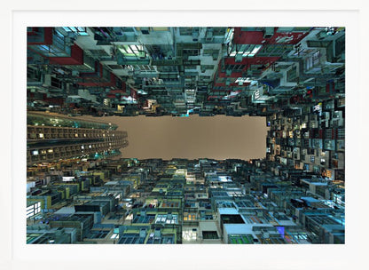A framed, low-angle photograph looking up from a courtyard at densely packed, colorful apartment buildings that form a rectangle around a blank, overcast sky at night. Print
