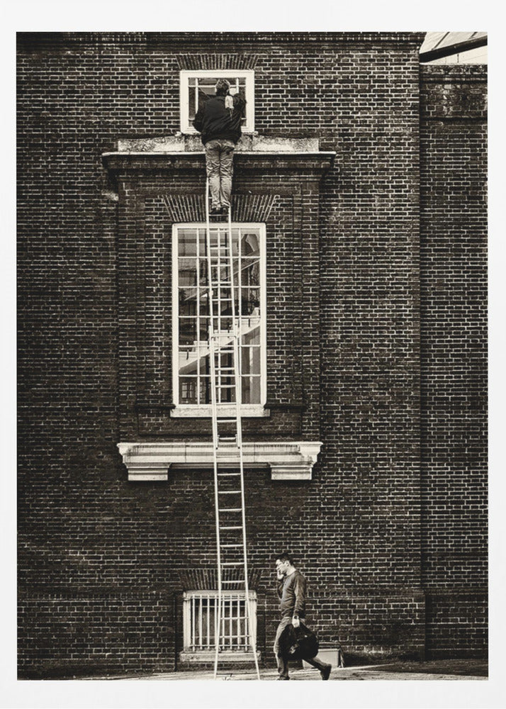 A striking black and white photograph of a man cleaning a small window high up on a brick building, standing precariously at the top of a very long ladder. Below, another man walks past on the street, seemingly unaware of the scene above. Artwork