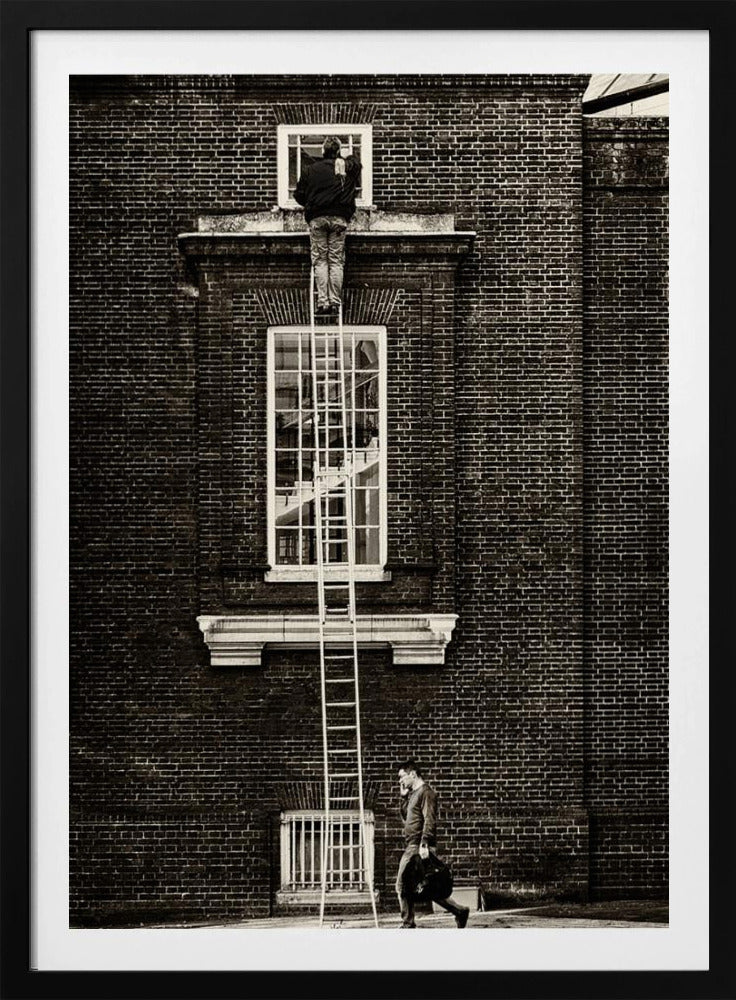 A striking black and white photograph of a man cleaning a small window high up on a brick building, standing precariously at the top of a very long ladder. Below, another man walks past on the street, seemingly unaware of the scene above. Artwork