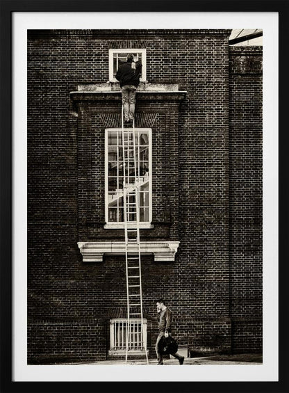 A striking black and white photograph of a man cleaning a small window high up on a brick building, standing precariously at the top of a very long ladder. Below, another man walks past on the street, seemingly unaware of the scene above. Artwork