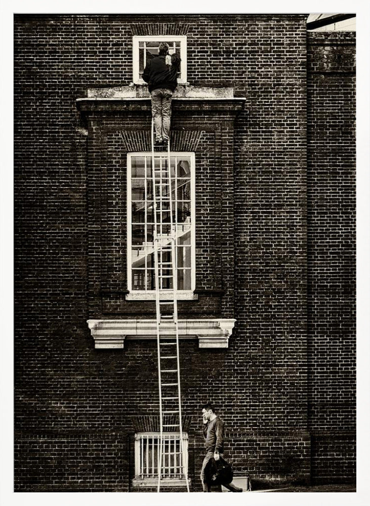 A striking black and white photograph of a man cleaning a small window high up on a brick building, standing precariously at the top of a very long ladder. Below, another man walks past on the street, seemingly unaware of the scene above. Artwork