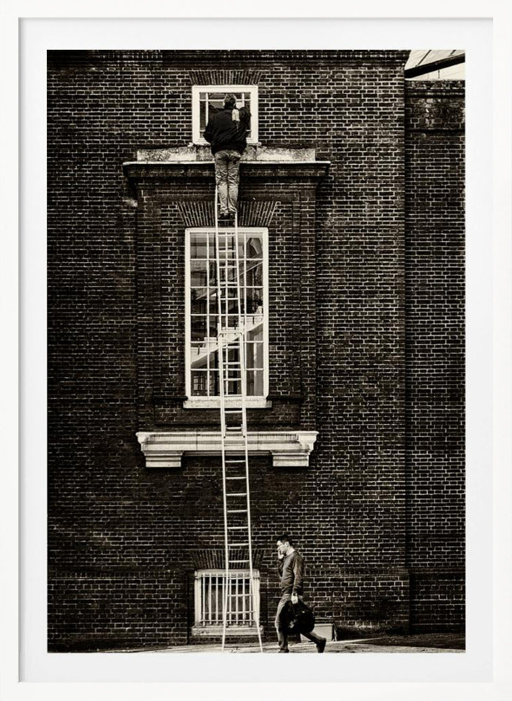 A striking black and white photograph of a man cleaning a small window high up on a brick building, standing precariously at the top of a very long ladder. Below, another man walks past on the street, seemingly unaware of the scene above. Artwork