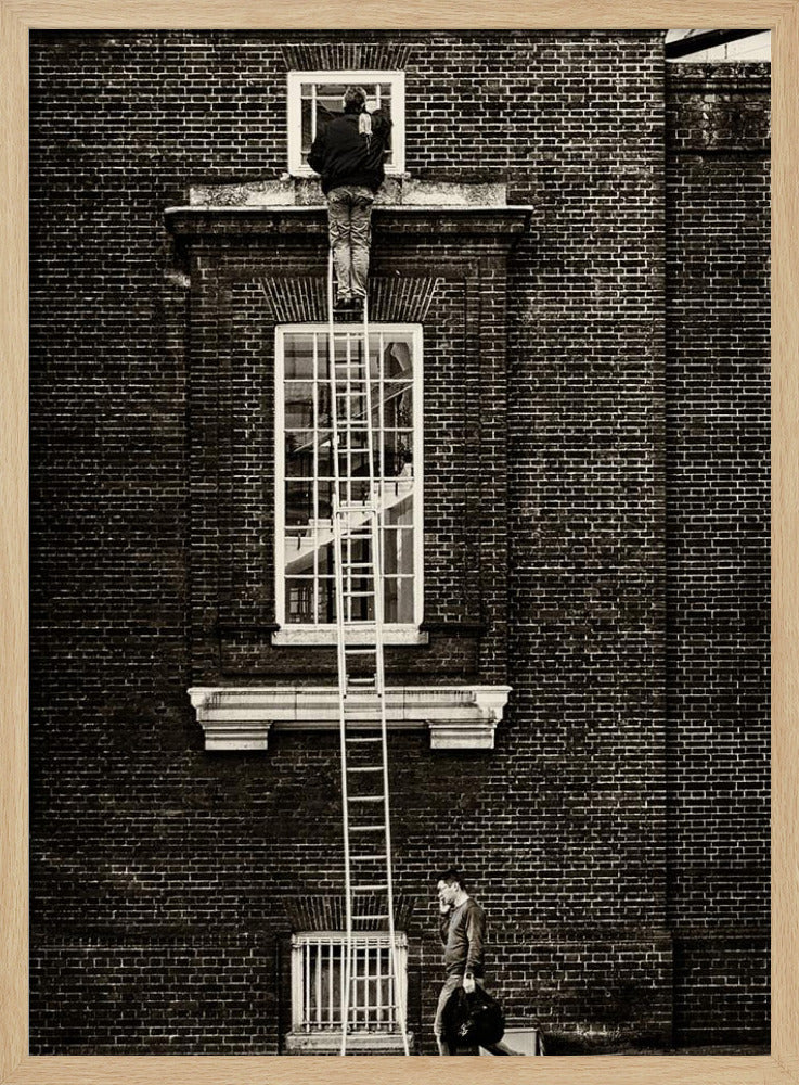 A striking black and white photograph of a man cleaning a small window high up on a brick building, standing precariously at the top of a very long ladder. Below, another man walks past on the street, seemingly unaware of the scene above. Artwork