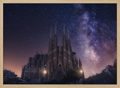 A fantastical night view of the Sagrada Familia in Barcelona, its intricate spires reaching up towards a magnificent, starry sky filled with the purple and pink hues of the Milky Way galaxy, all enclosed in a silver frame. Artwork