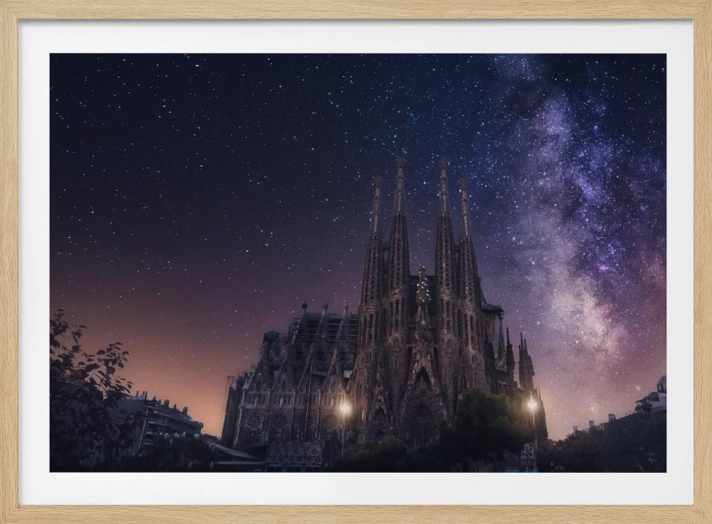 A fantastical night view of the Sagrada Familia in Barcelona, its intricate spires reaching up towards a magnificent, starry sky filled with the purple and pink hues of the Milky Way galaxy, all enclosed in a silver frame. Artwork