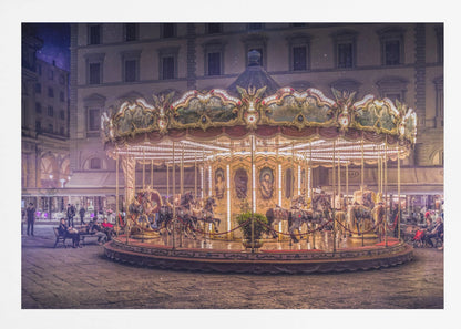 A beautifully illuminated vintage carousel with ornate horses in a European cobblestone plaza at night. The carousel is the central focus, glowing with warm lights against a backdrop of historic buildings and a starry purple sky. Poster