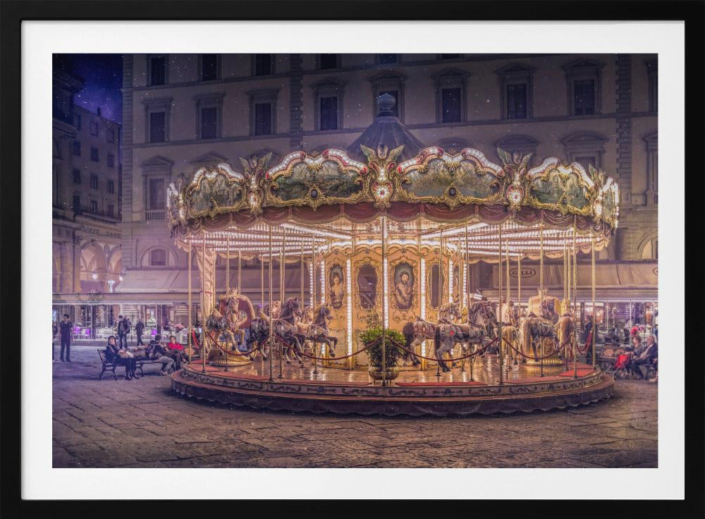 A beautifully illuminated vintage carousel with ornate horses in a European cobblestone plaza at night. The carousel is the central focus, glowing with warm lights against a backdrop of historic buildings and a starry purple sky. Poster