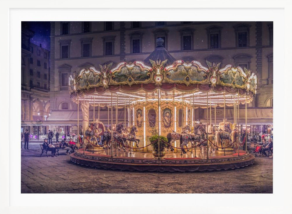 A beautifully illuminated vintage carousel with ornate horses in a European cobblestone plaza at night. The carousel is the central focus, glowing with warm lights against a backdrop of historic buildings and a starry purple sky. Poster