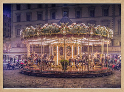 A beautifully illuminated vintage carousel with ornate horses in a European cobblestone plaza at night. The carousel is the central focus, glowing with warm lights against a backdrop of historic buildings and a starry purple sky. Poster