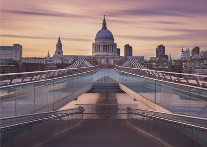 A photograph looking down the center of the Millennium Bridge in London, leading the eye directly to St. Paul's Cathedral, which is centered in the background under a beautiful purple and orange sunset sky. Print