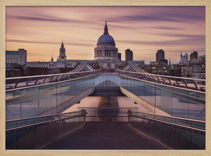 A photograph looking down the center of the Millennium Bridge in London, leading the eye directly to St. Paul's Cathedral, which is centered in the background under a beautiful purple and orange sunset sky. Print