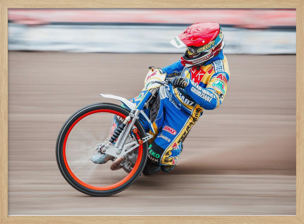 A speedway motorcycle racer in a blue and yellow suit with a red helmet leans sharply into a turn on a dirt track, with motion blur in the background conveying a sense of high speed. Print
