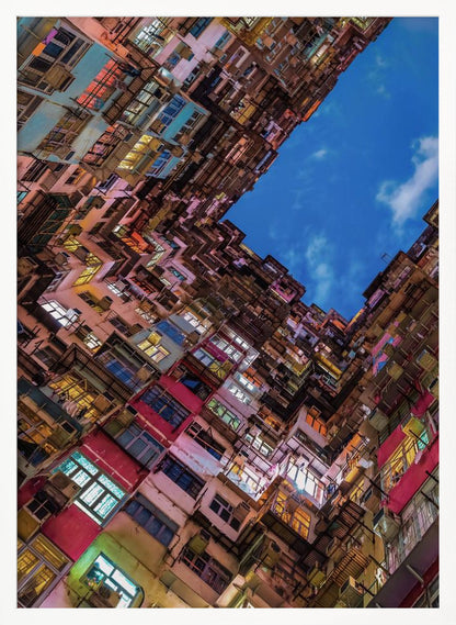 A dramatic worm's-eye view looking up at colorful, densely packed high-rise apartment buildings that create a geometric frame around a patch of deep blue sky. Wall Art