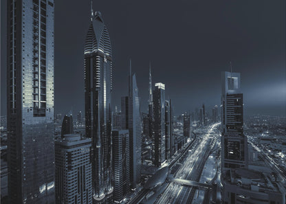 A framed, blue-toned nighttime photograph of a futuristic city skyline from an elevated perspective, featuring illuminated skyscrapers and light trails from traffic on a major highway stretching into the distance. Poster