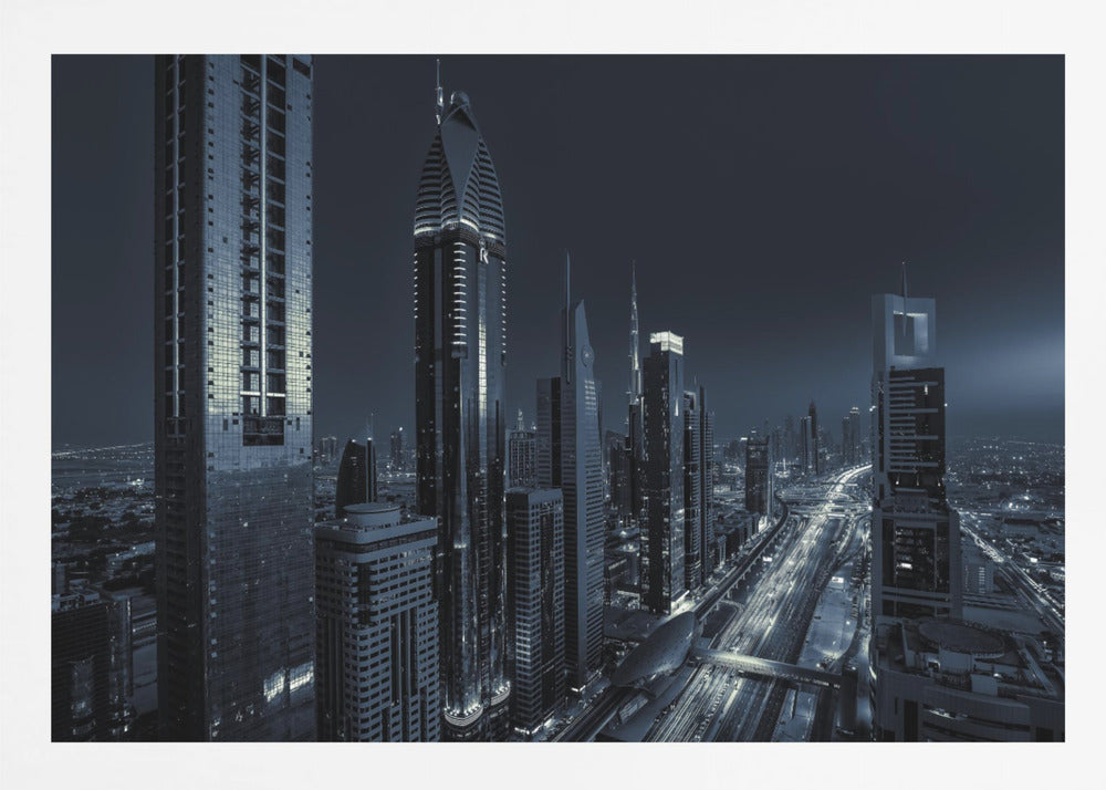 A framed, blue-toned nighttime photograph of a futuristic city skyline from an elevated perspective, featuring illuminated skyscrapers and light trails from traffic on a major highway stretching into the distance. Poster
