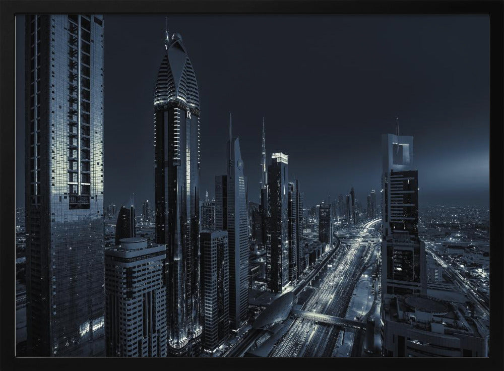 A framed, blue-toned nighttime photograph of a futuristic city skyline from an elevated perspective, featuring illuminated skyscrapers and light trails from traffic on a major highway stretching into the distance. Poster