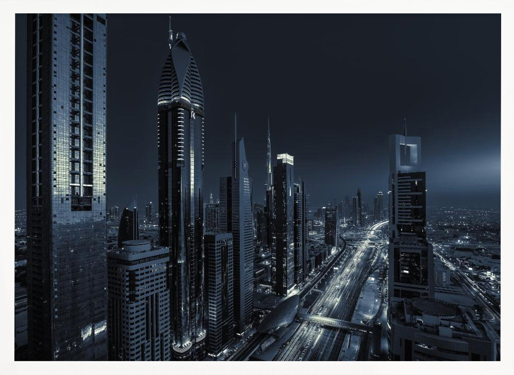 A framed, blue-toned nighttime photograph of a futuristic city skyline from an elevated perspective, featuring illuminated skyscrapers and light trails from traffic on a major highway stretching into the distance. Poster