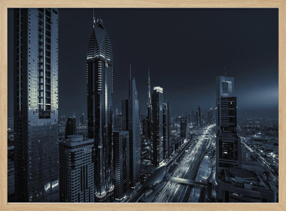 A framed, blue-toned nighttime photograph of a futuristic city skyline from an elevated perspective, featuring illuminated skyscrapers and light trails from traffic on a major highway stretching into the distance. Poster