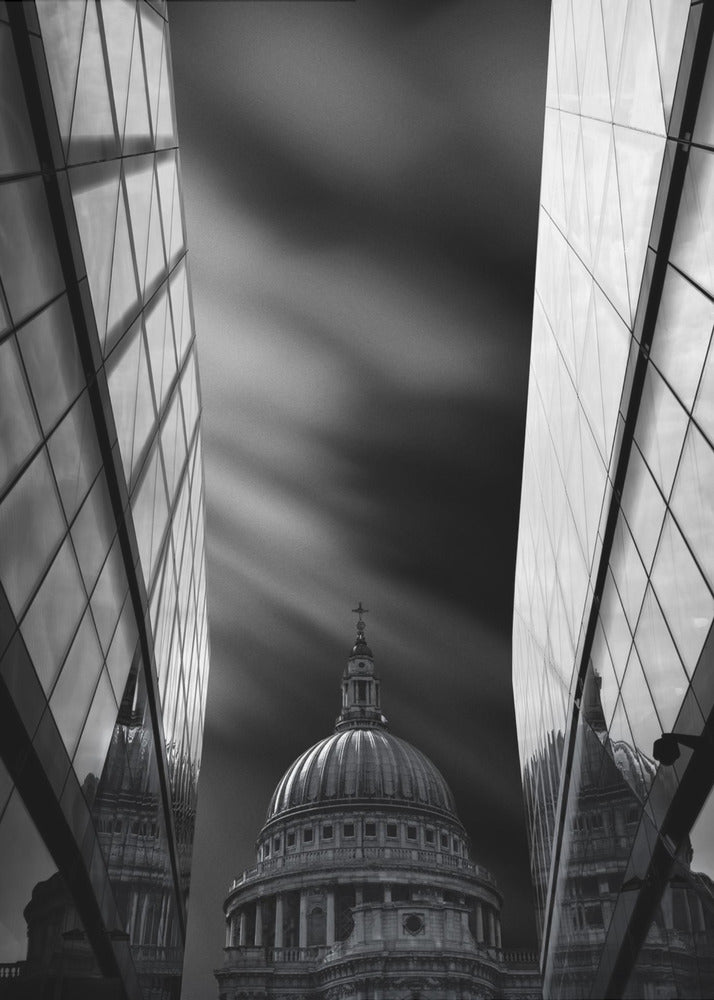A dramatic black and white, low-angle photograph of St. Paul's Cathedral in London, framed between two modern, reflective glass skyscrapers. A long exposure effect blurs the clouds in the sky, creating streaks of light and shadow behind the cathedral's dome. Poster