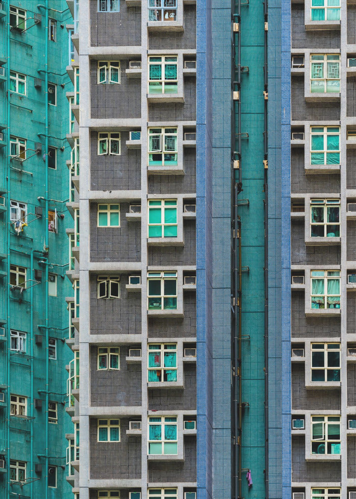 A striking close-up of two densely packed apartment buildings, one with a teal tiled facade and the other with a grey and blue tiled facade, creating a strong pattern of repeating windows and geometric lines. Decor
