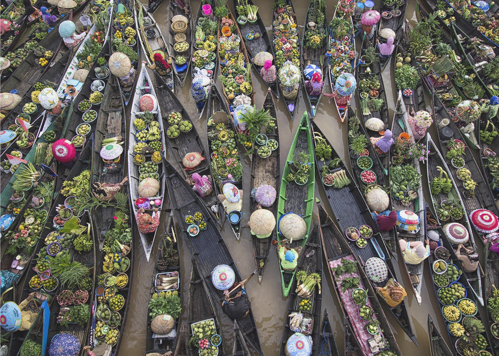 An aerial photograph of a crowded floating market in Southeast Asia, with dozens of narrow wooden boats filled with vibrant green produce and colorful wares on a brown river. Poster