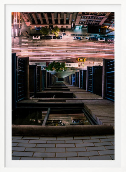 A dizzying bird's-eye view looking straight down the side of a skyscraper into a busy city street at night, with long exposure light trails from traffic creating streaks of red and white below. Wall Art