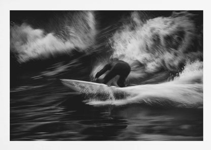 A dynamic black and white action photograph of a surfer in a dark wetsuit, crouched low on a surfboard while riding a powerful wave. Motion blur captures the speed and energy of the moment, with white water spray exploding around the surfer against the dark ocean. Print