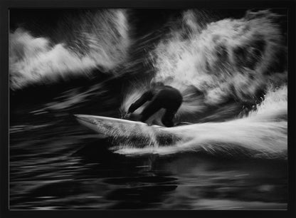 A dynamic black and white action photograph of a surfer in a dark wetsuit, crouched low on a surfboard while riding a powerful wave. Motion blur captures the speed and energy of the moment, with white water spray exploding around the surfer against the dark ocean. Print