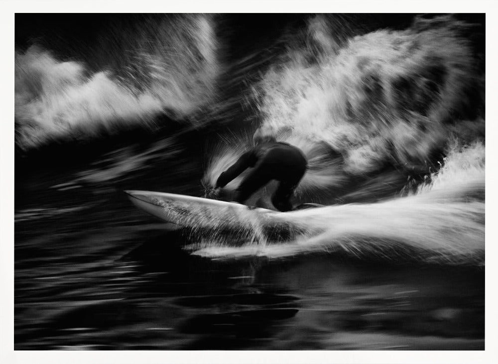 A dynamic black and white action photograph of a surfer in a dark wetsuit, crouched low on a surfboard while riding a powerful wave. Motion blur captures the speed and energy of the moment, with white water spray exploding around the surfer against the dark ocean. Print