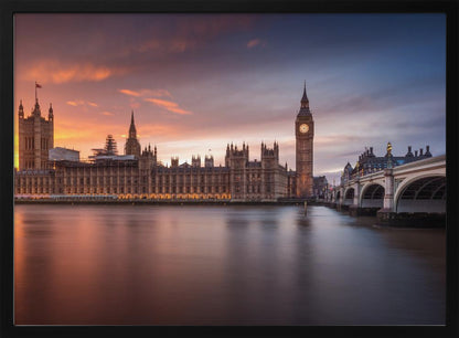 A framed photograph of the Houses of Parliament and Big Ben in London at sunset, with a dramatic orange and purple sky reflecting in the calm waters of the River Thames. Artwork