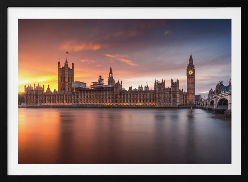 A framed photograph of the Houses of Parliament and Big Ben in London at sunset, with a dramatic orange and purple sky reflecting in the calm waters of the River Thames. Artwork