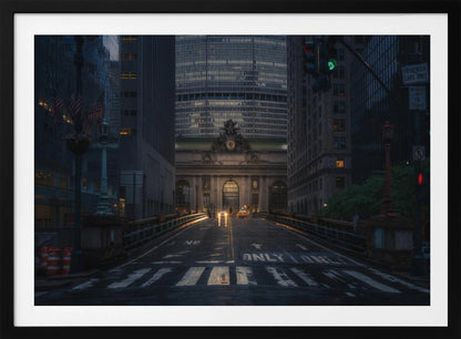 A moody photograph of a wet city street at dusk, leading towards the illuminated facade of Grand Central Terminal in New York City, which is framed by tall, modern skyscrapers. Decor
